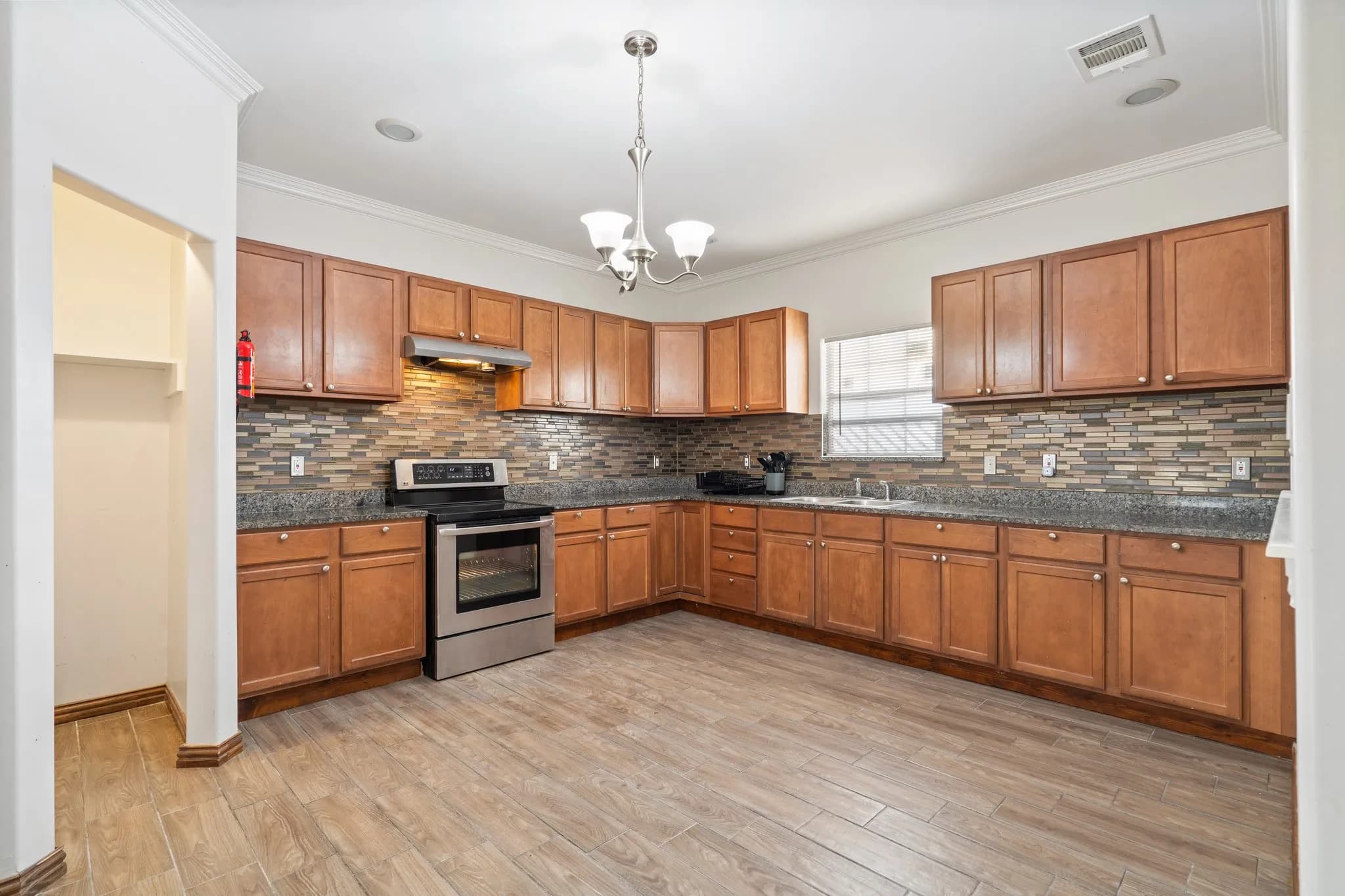 Well-maintained kitchen with wood cabinetry, granite countertops, and a tiled backsplash in a professionally managed property